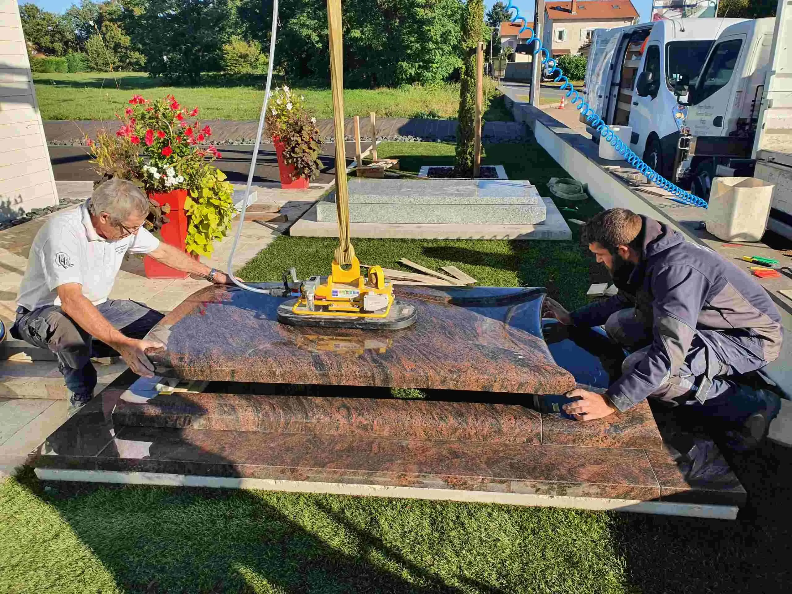 Pose minutieuse d'une pierre tombale en granit bicolore par deux marbriers.
