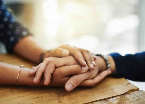 Soutien et réconfort lors d'un deuil par un geste d'empathie, mains jointes.